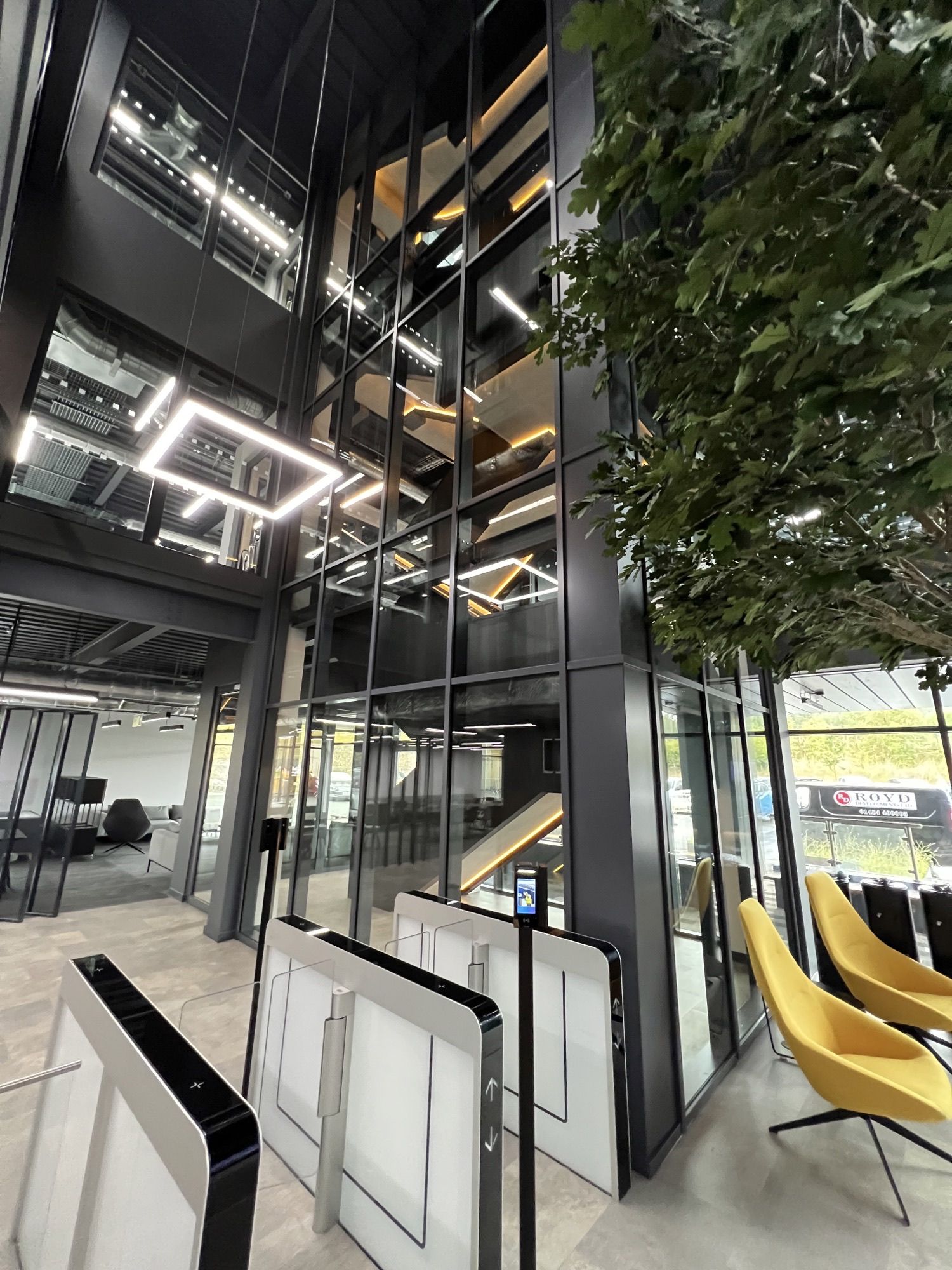 Modernes Bürogebäude mit künstlichem Baum und Treppenhaus eingeglast